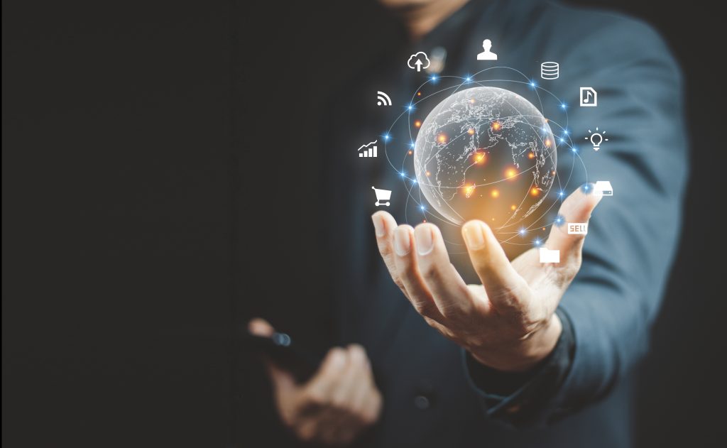 A businessman holding a digital globe surrounded by glowing network connections and technology icons, representing global connectivity, innovation, and emerging trends.