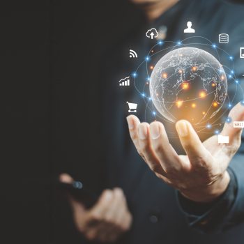 A businessman holding a digital globe surrounded by glowing network connections and technology icons, representing global connectivity, innovation, and emerging trends.