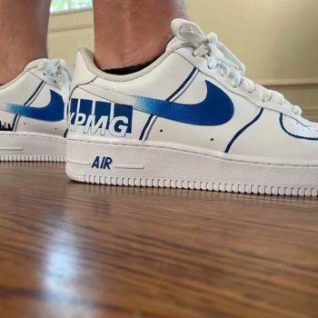 White Nike Air Force 1 sneakers customised with the KPMG logo and blue swoosh design.